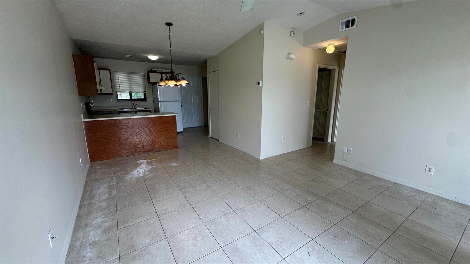 An open-concept living area features light-colored tile flooring, a kitchen island, and neutral walls — 5045 SE Primrose Way, Stuart FL 34997, STUART, FL