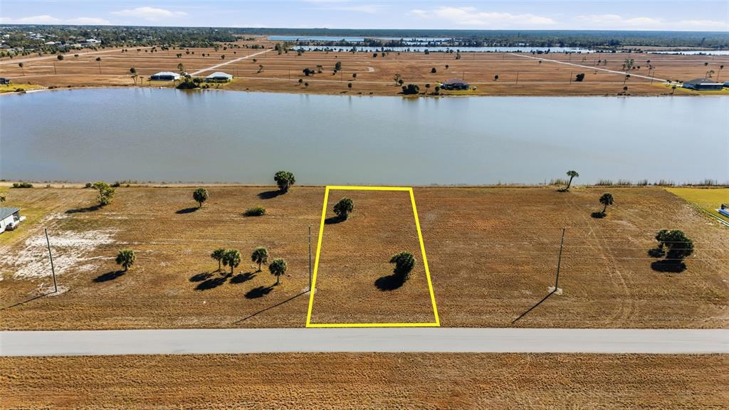 An aerial view shows a vacant rectangular lot outlined in yellow bordering a large lake — 32 YELLOWHAMMER DRIVE, PLACIDA, FL
