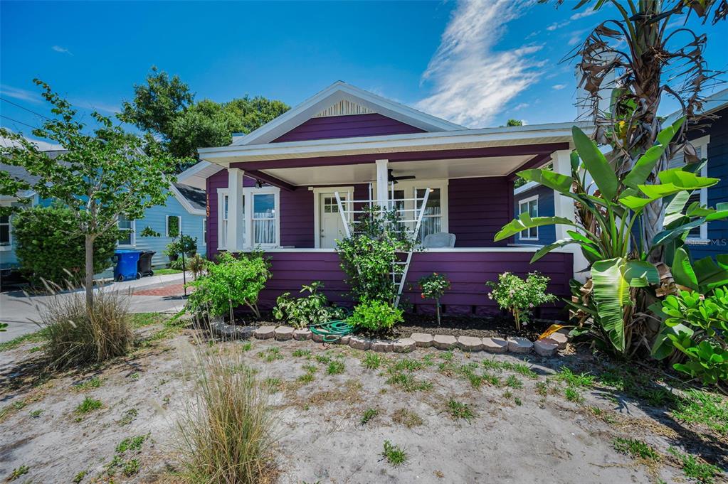 A purple bungalow features a front porch with white columns and a landscaped yard — 1100 35TH AVENUE N, ST PETERSBURG, FL