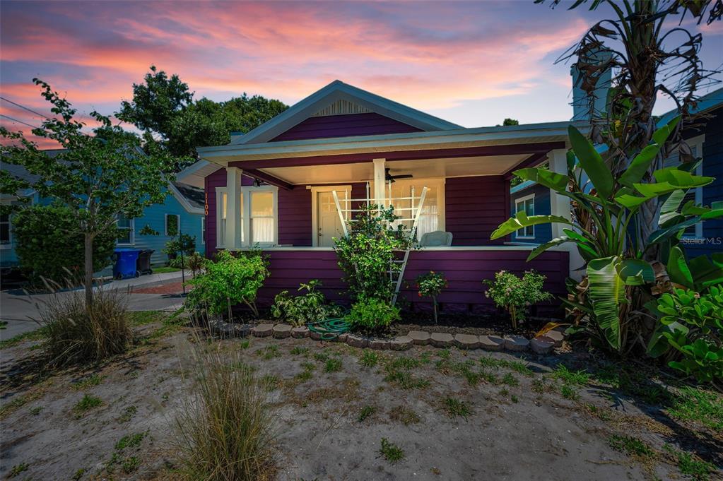A purple bungalow with a front porch and landscaping sits under a sunset sky — 1100 35TH AVENUE N, ST PETERSBURG, FL