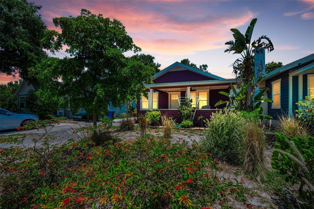 A purple house with a front porch sits behind a garden at sunset — 1100 35TH AVENUE N, ST PETERSBURG, FL