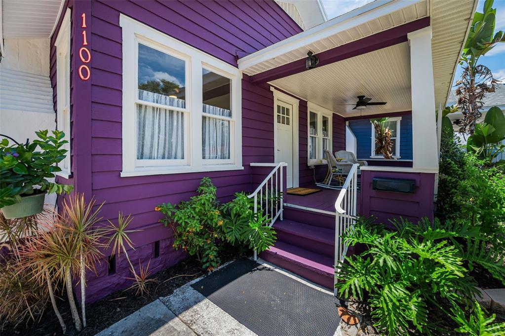 A purple house with a front porch, white trim, and lush green landscaping — 1100 35TH AVENUE N, ST PETERSBURG, FL
