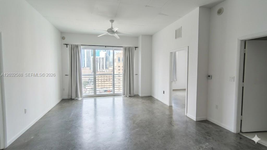An empty room with concrete floors, white walls, a ceiling fan, and a balcony view — 133 NE 2nd Ave # 1906, Miami FL 33132, MIAMI, FL
