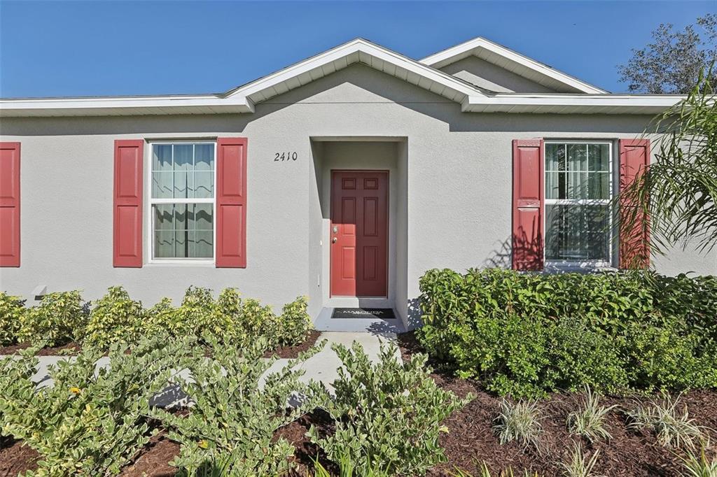 A single-story house exterior features a red front door, red shutters, and landscaped bushes — 2410 PARK AVENUE, INDIAN LAKE ESTATES, FL