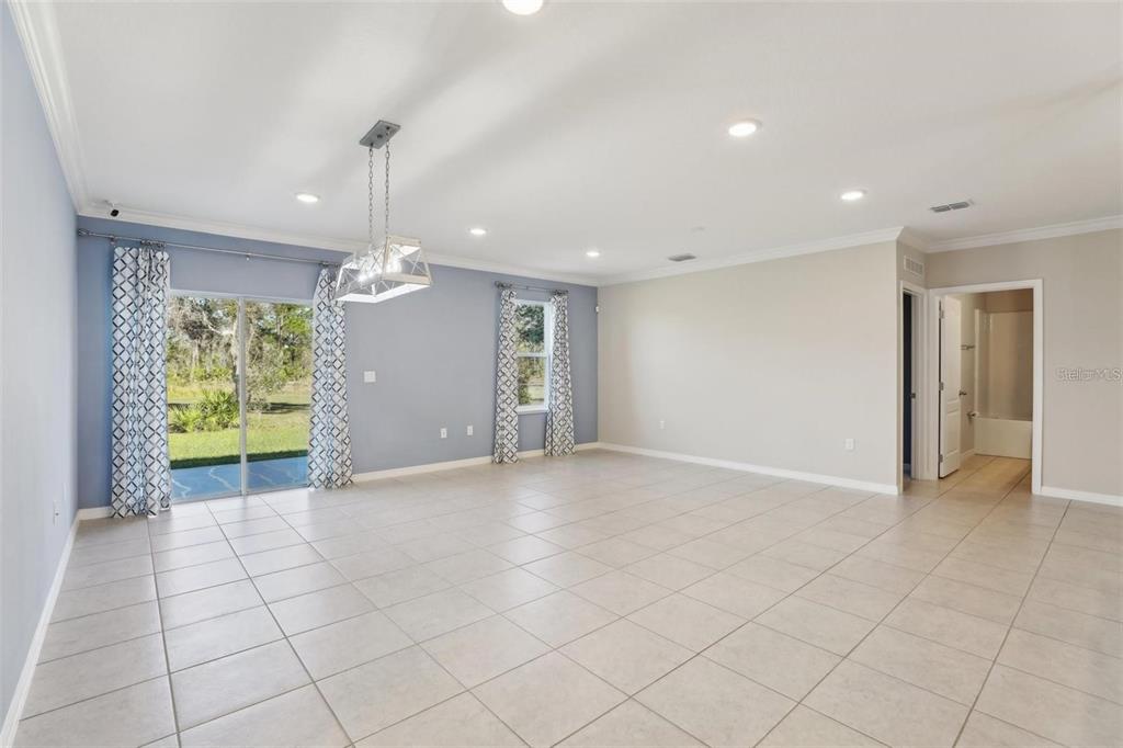 A spacious living room features light tile flooring, a blue accent wall, and sliding glass doors — 2410 PARK AVENUE, INDIAN LAKE ESTATES, FL