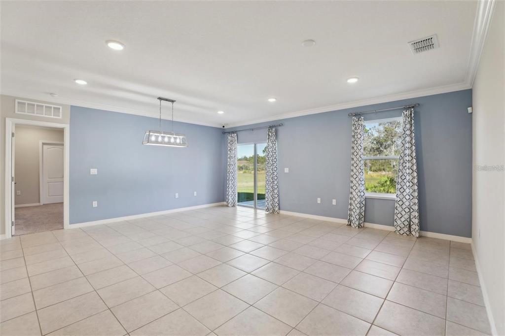 A spacious room with light blue walls, tile flooring, a dining chandelier, and sliding doors — 2410 PARK AVENUE, INDIAN LAKE ESTATES, FL