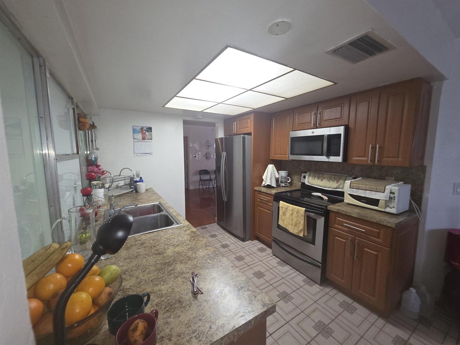 A kitchen features wood cabinets, stainless steel appliances, a double sink, and a drop ceiling — 5261 NW 14th Place, Lauderhill FL 33313, LAUDERHILL, FL