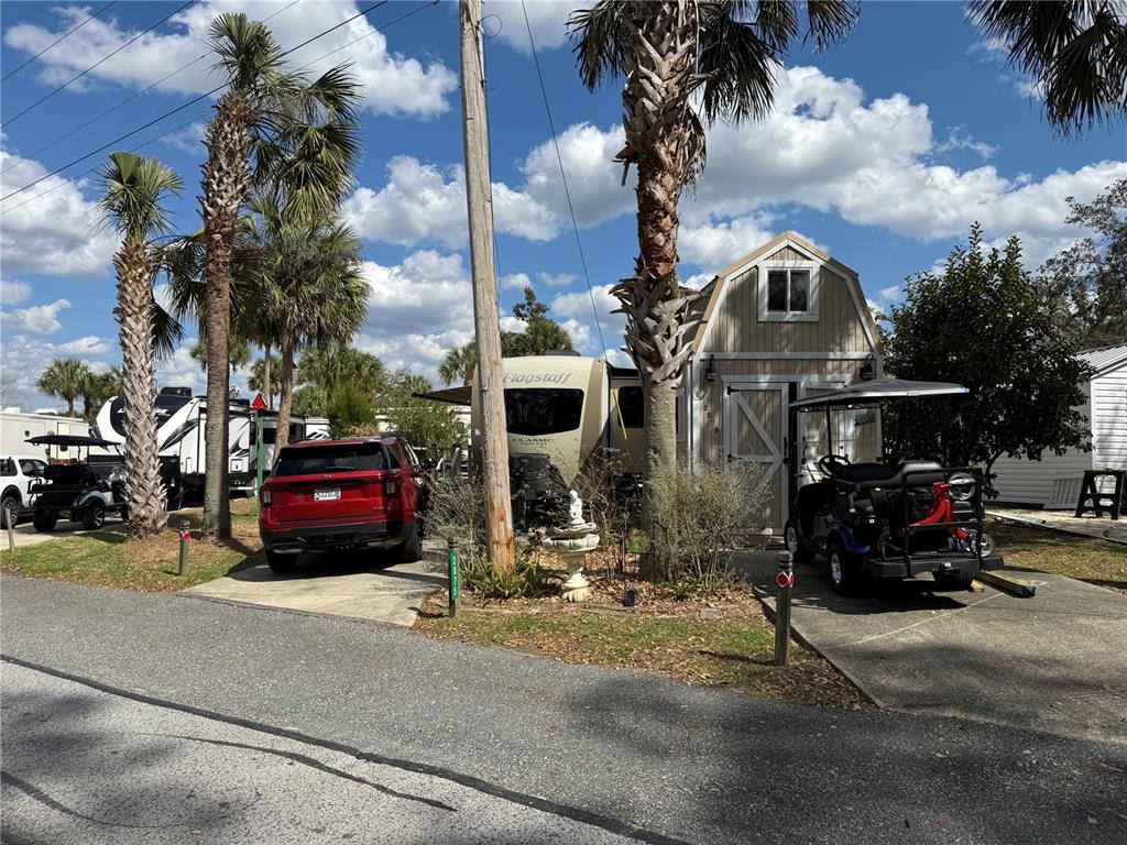 A red SUV is parked next to a travel trailer and a small storage shed — 2875 NE 102ND AVENUE ROAD, SILVER SPRINGS, FL