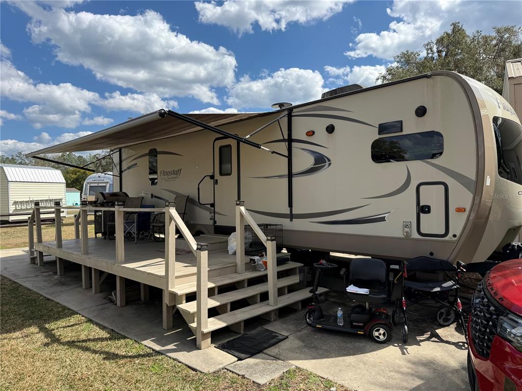 A tan Flagstaff travel trailer with an attached wooden deck sits on a concrete pad — 2875 NE 102ND AVENUE ROAD, SILVER SPRINGS, FL
