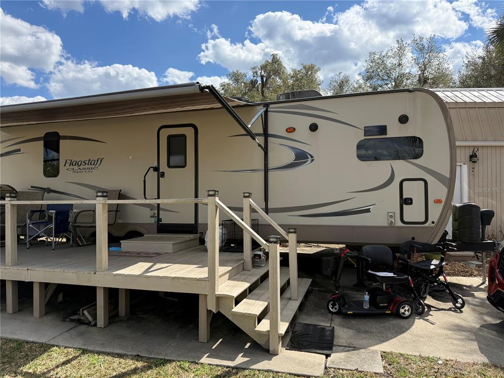 A tan Flagstaff travel trailer with an attached wooden deck sits on a concrete pad — 2875 NE 102ND AVENUE ROAD, SILVER SPRINGS, FL