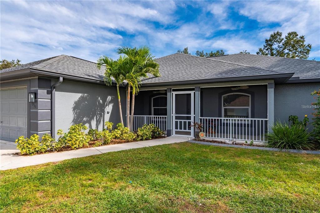 A gray single-story house features a front porch with a white railing and screen door — 5250 SUNNYVALE ROAD, NORTH PORT, FL