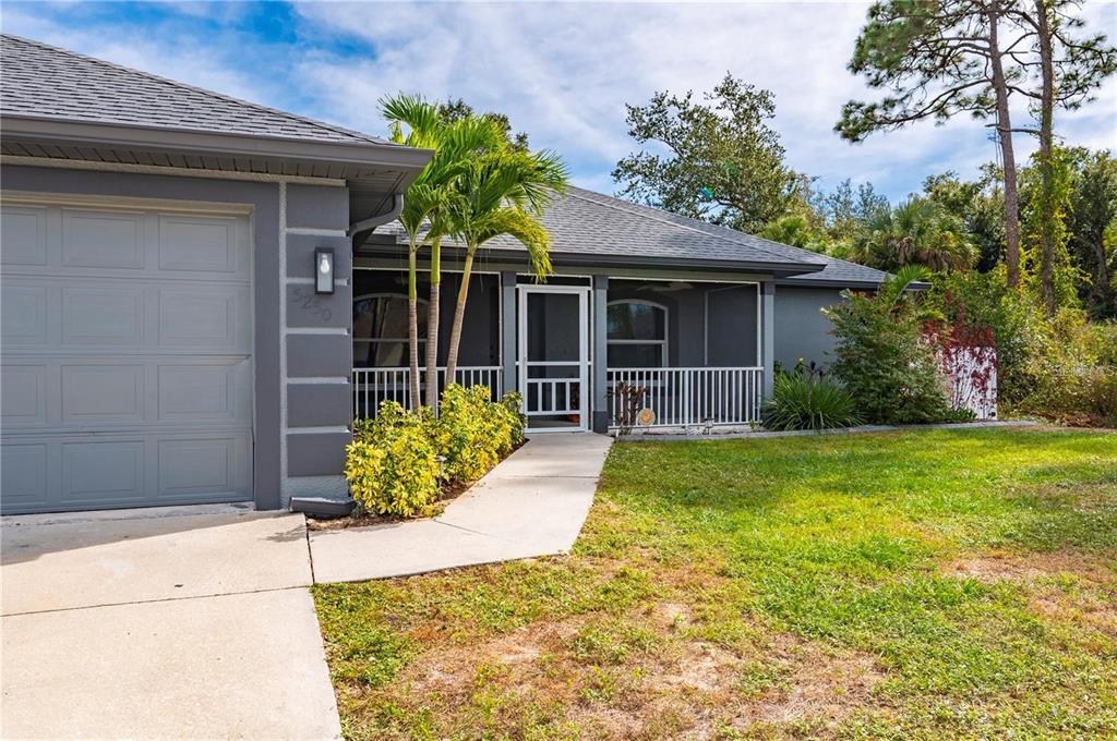 A gray house exterior features a garage, a screened-in porch, and a concrete walkway — 5250 SUNNYVALE ROAD, NORTH PORT, FL
