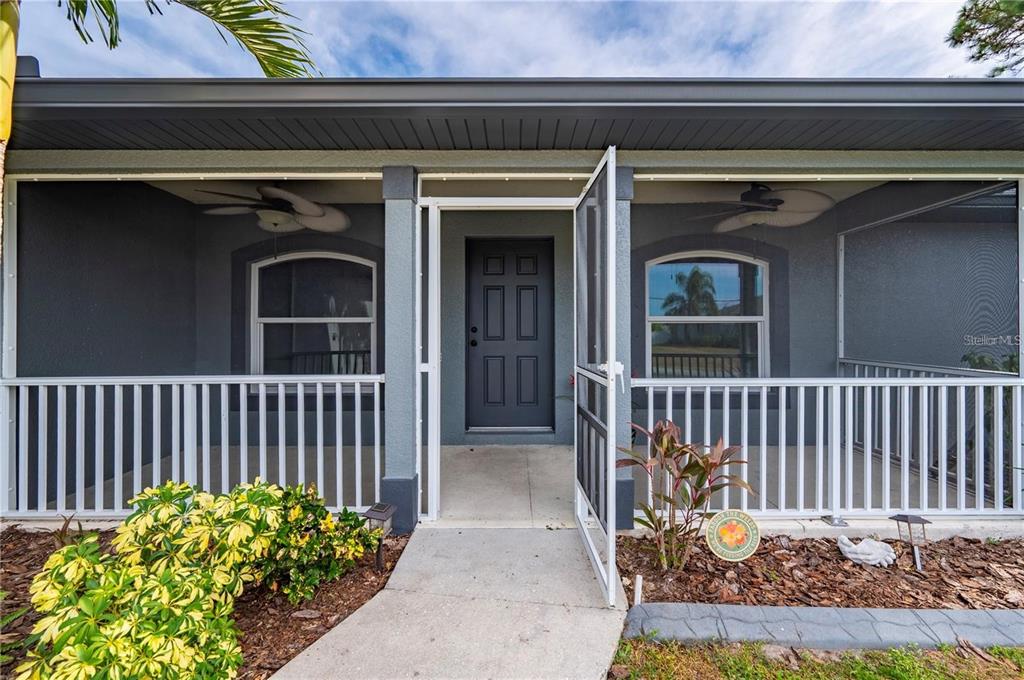 A gray house features a screened-in front porch with white railings and a dark door — 5250 SUNNYVALE ROAD, NORTH PORT, FL