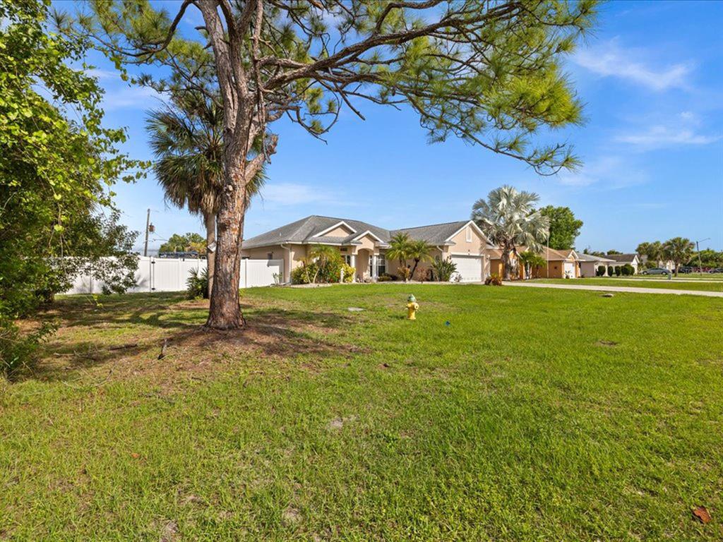 A single-story house with a lawn, a fire hydrant, and trees under a blue sky — 32 ORLANDO BOULEVARD, PORT CHARLOTTE, FL