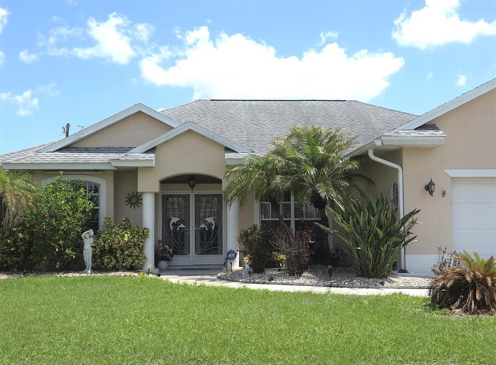 A single-story house with a beige stucco exterior, a gray shingled roof, and a front lawn — 32 ORLANDO BOULEVARD, PORT CHARLOTTE, FL