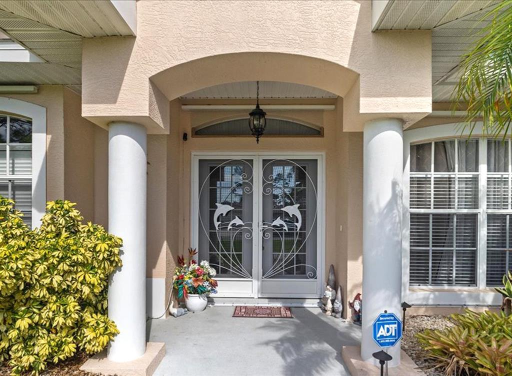 The front entrance of a house features white double screen doors with dolphin metalwork — 32 ORLANDO BOULEVARD, PORT CHARLOTTE, FL