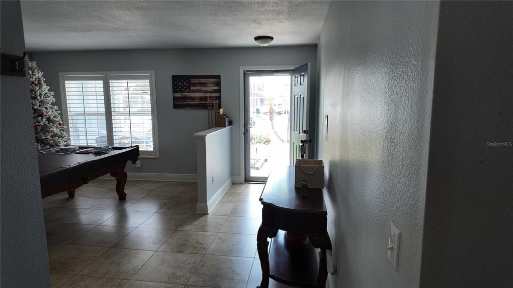 A tiled entryway features a pool table, a half-wall, and a front door opening outside — 1042 HORSESHOE FALLS DRIVE, ORLANDO, FL