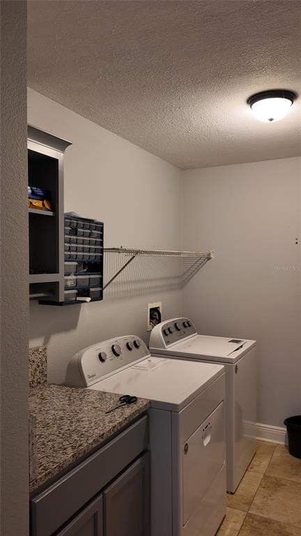 A laundry room features a washer, dryer, granite countertop, gray cabinetry, and wire shelving — 1042 HORSESHOE FALLS DRIVE, ORLANDO, FL