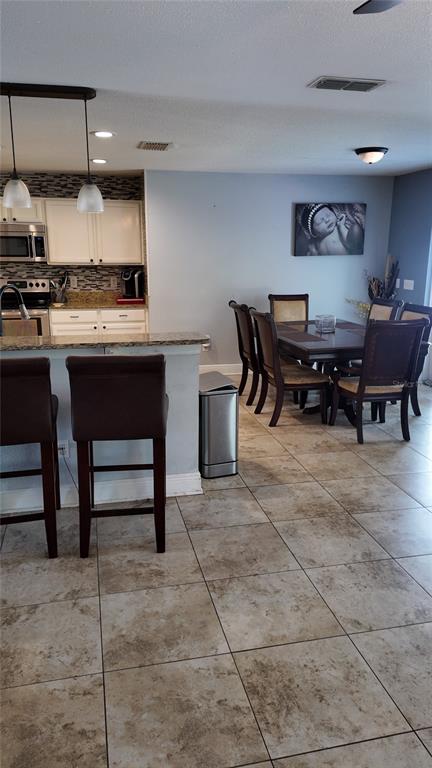 A kitchen with a breakfast bar and an adjacent dining area featuring tiled floors — 1042 HORSESHOE FALLS DRIVE, ORLANDO, FL