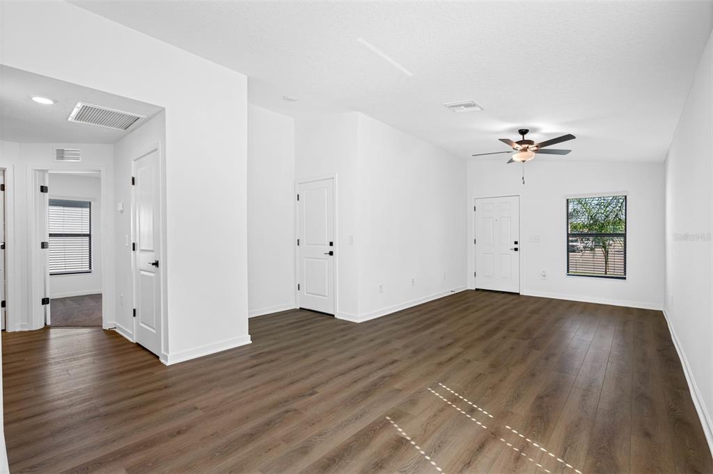 An empty room with white walls, wood-look flooring, a ceiling fan, and a front door — 537 BLACKTHORN DRIVE, LAKELAND, FL
