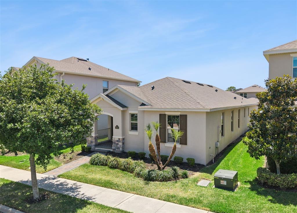 A single-story suburban house with a tan stucco exterior, stone accents, and a paved walkway — 10294 MERRYMEETING BAY DRIVE, WINTER GARDEN, FL
