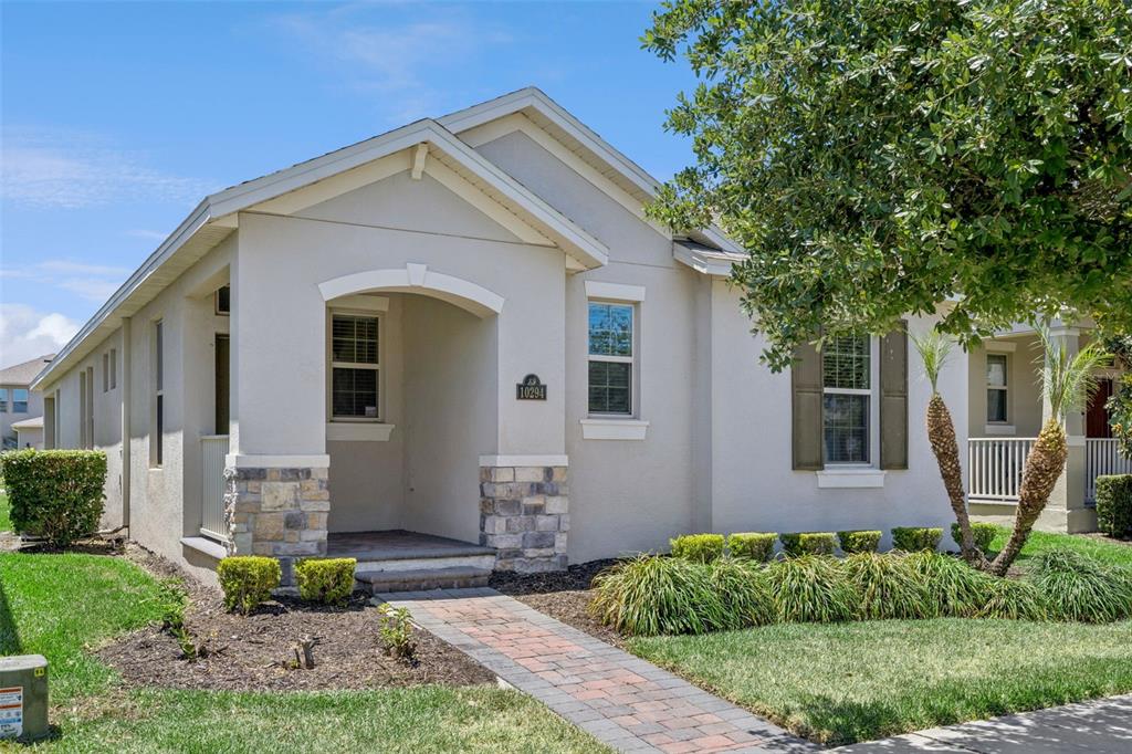 A single-story house with a stone-accented entryway, a brick walkway, and a small front lawn — 10294 MERRYMEETING BAY DRIVE, WINTER GARDEN, FL