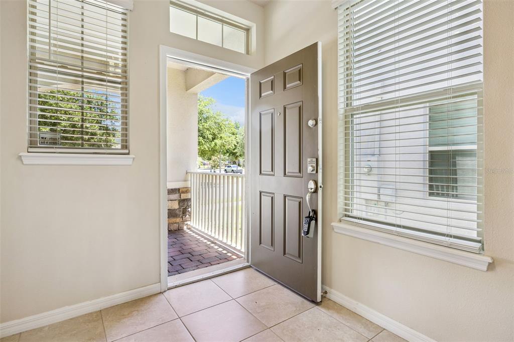 An entryway with tile flooring, a brown front door, and windows with white blinds — 10294 MERRYMEETING BAY DRIVE, WINTER GARDEN, FL