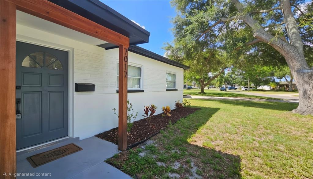 The exterior of a white house features a blue front door and wooden porch supports — 7017 20TH STREET N, ST PETERSBURG, FL