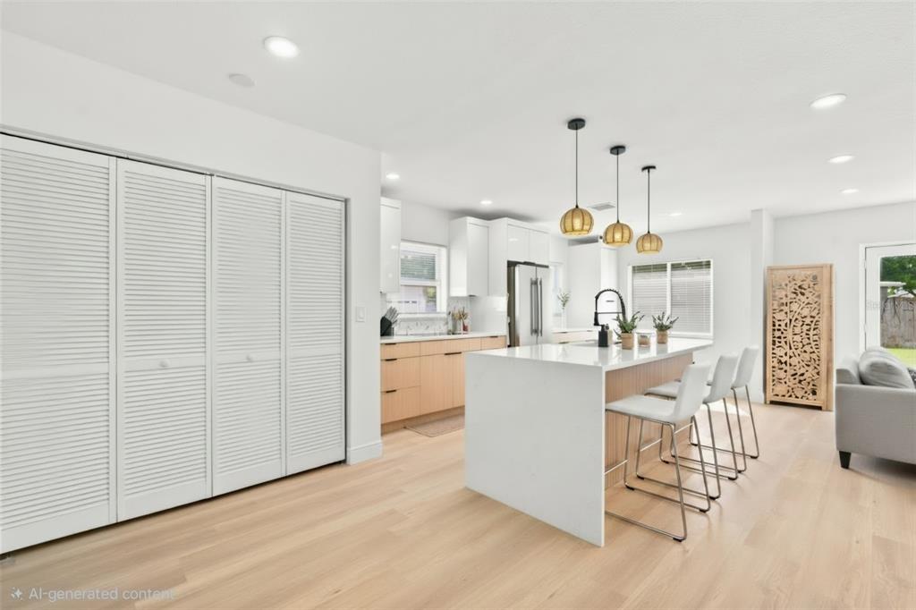 A modern kitchen features a white island with bar stools, light wood cabinets, and flooring — 7017 20TH STREET N, ST PETERSBURG, FL