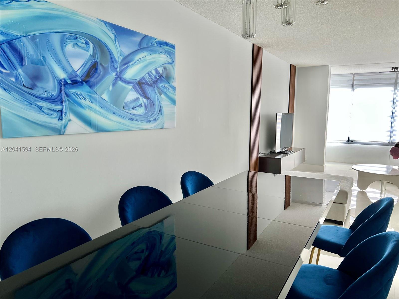 A dining area features a black table, blue velvet chairs, and abstract wall art — 2551 Aragon Blvd # 310, Sunrise FL 33322, SUNRISE, FL