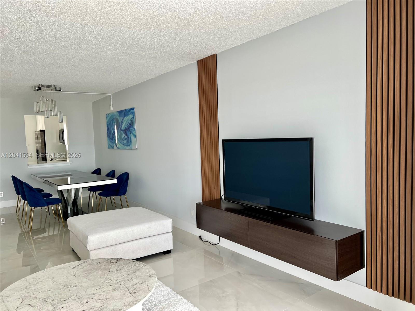 A living room features a wall-mounted television, wood slat accents, and a floating media console — 2551 Aragon Blvd # 310, Sunrise FL 33322, SUNRISE, FL