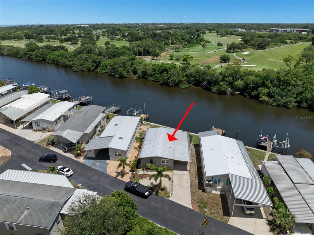 An aerial view shows a waterfront house with a metal roof and a private dock — 460 MOUNT OAK AVENUE NE UNIT 745, ST PETERSBURG, FL