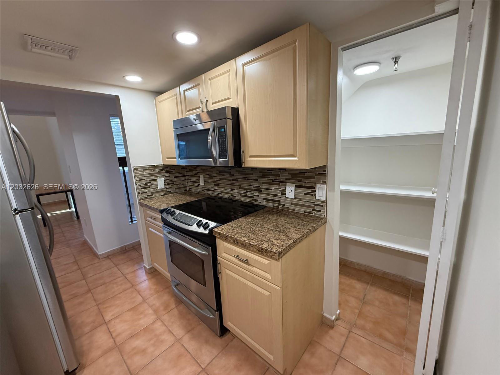 A kitchen features light wood cabinets, granite countertops, stainless steel appliances, and a walk-in pantry — 10641 SW 108 AVE # 3I, Miami FL 33176, MIAMI, FL
