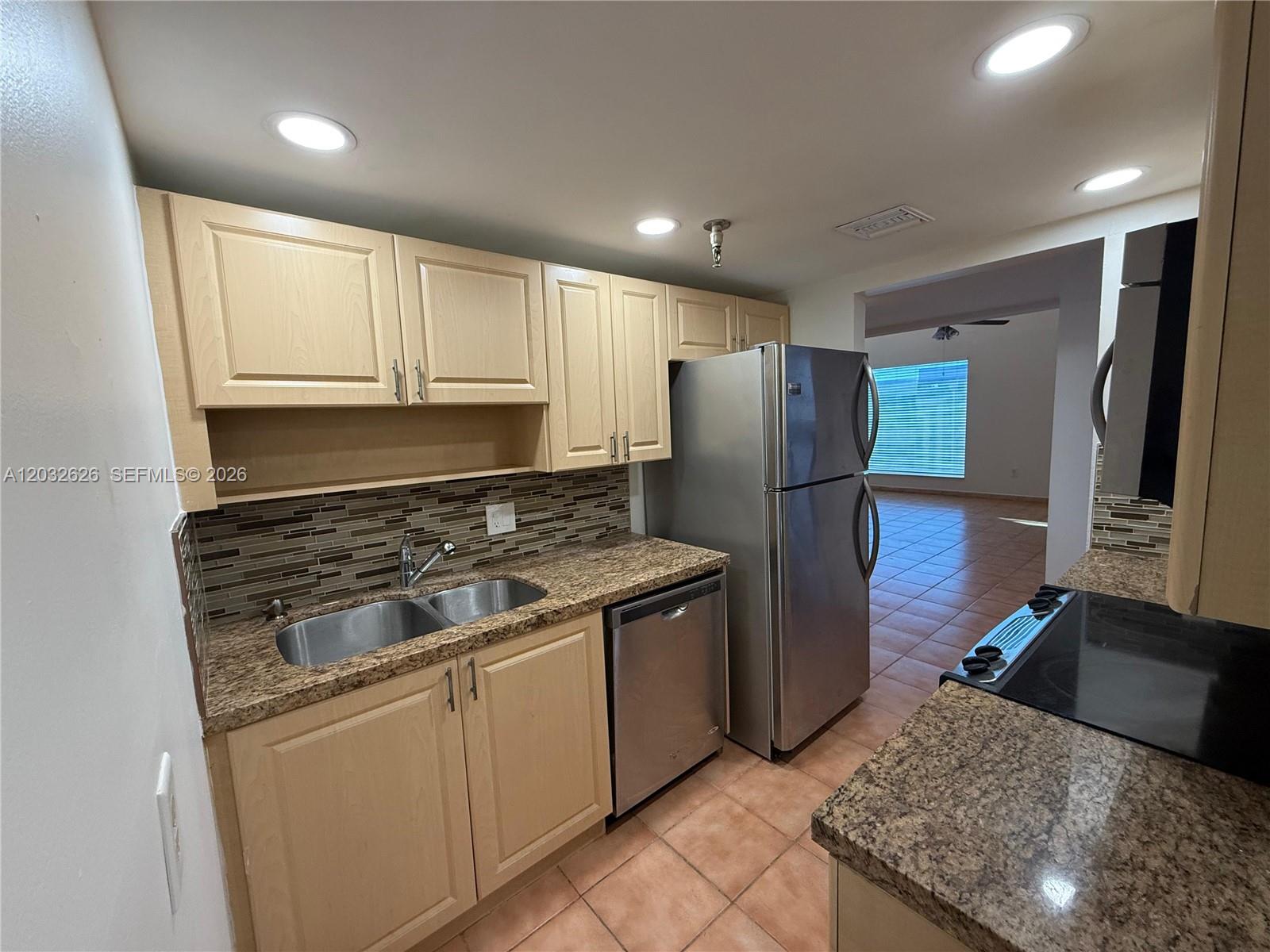 A kitchen features light wood cabinets, granite countertops, stainless steel appliances, and tiled flooring — 10641 SW 108 AVE # 3I, Miami FL 33176, MIAMI, FL