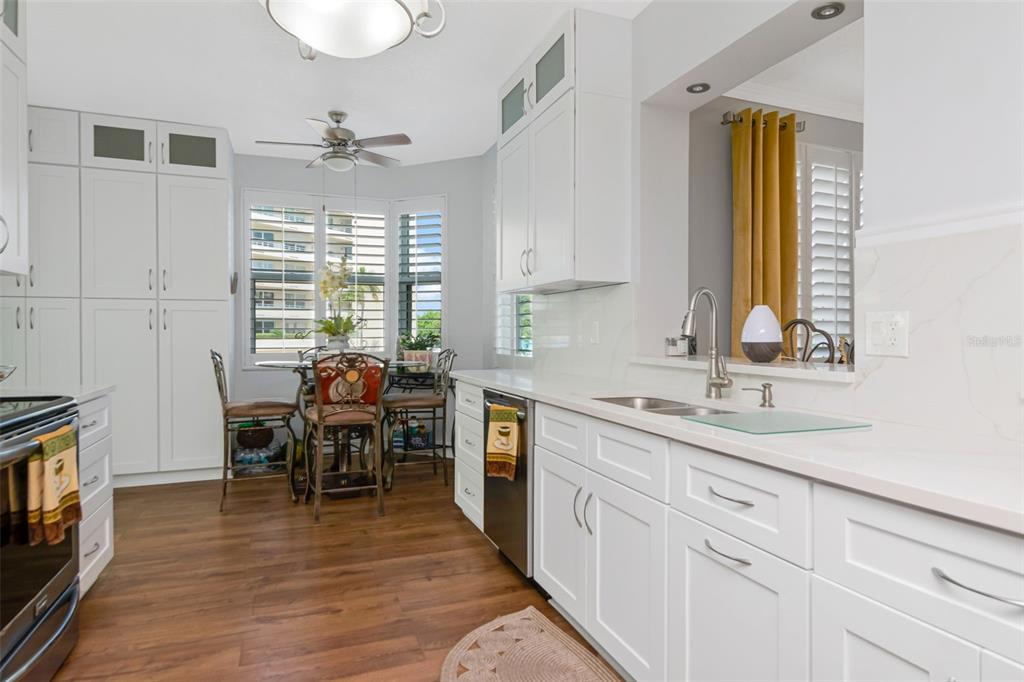 A kitchen features white cabinets, quartz countertops, stainless steel appliances, and a dining area — 7979 SAILBOAT KEY BOULEVARD S UNIT 101, SOUTH PASADENA, FL