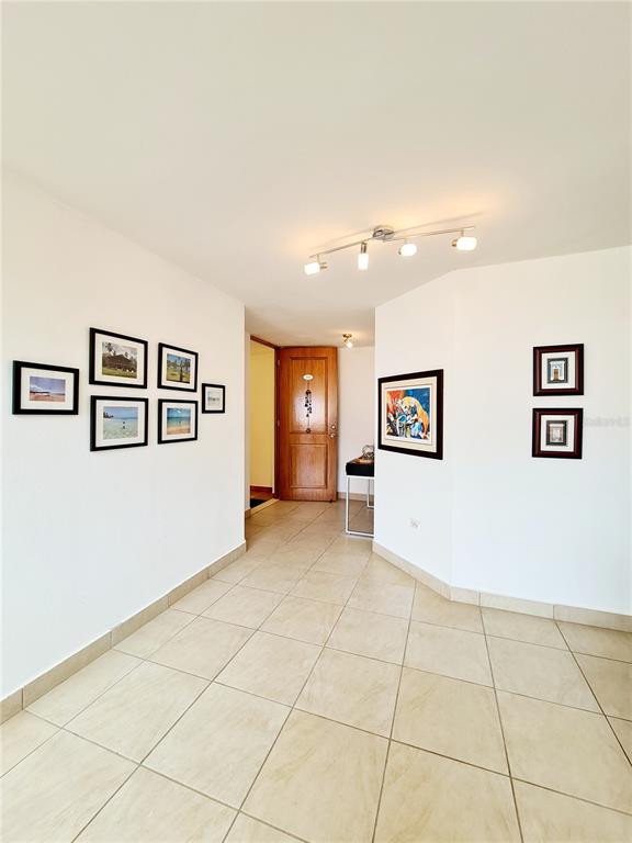A bright entryway features white walls, tiled floors, a wooden door, and several framed pictures — 500 CALLE ANDALUCÍA UNIT 508-4, AGUADILLA, PR