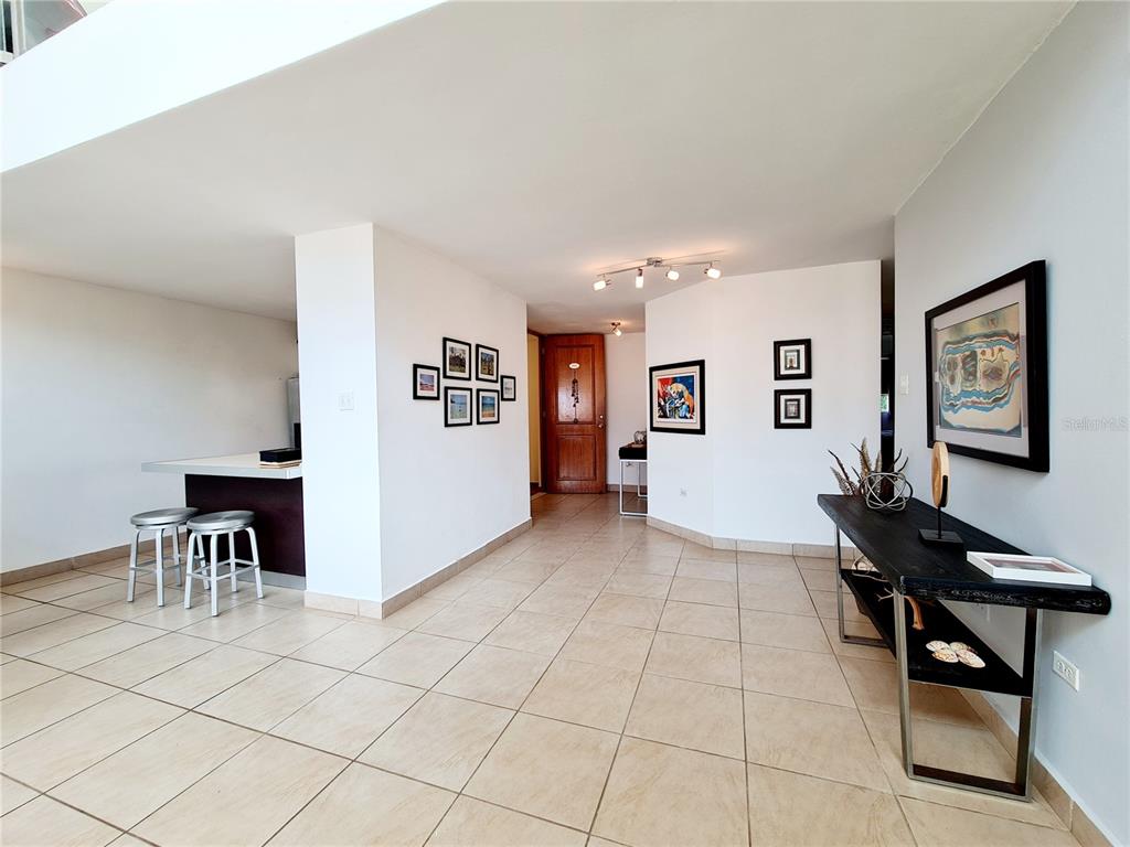 A tiled entryway leads to a kitchen with a breakfast bar and a wooden door — 500 CALLE ANDALUCÍA UNIT 508-4, AGUADILLA, PR