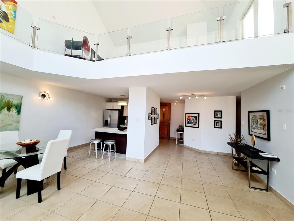 A bright, open-concept living area features a dining space, kitchen with bar seating, and a loft — 500 CALLE ANDALUCÍA UNIT 508-4, AGUADILLA, PR