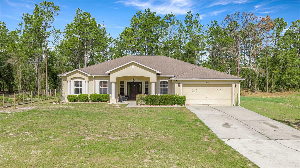 A single-story house with a beige stucco exterior, a two-car garage, and a front porch — 8778 SW 127TH AVENUE, DUNNELLON, FL