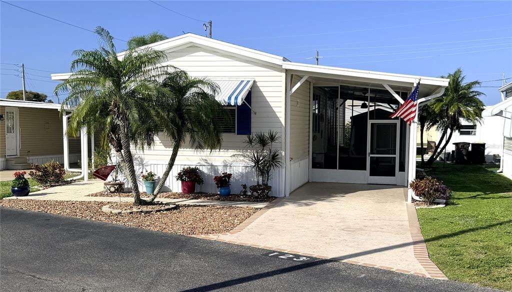 A single-story manufactured home with a carport, screened porch, and palm trees in the front — 10100 BURNT STORE ROAD UNIT 123, PUNTA GORDA, FL