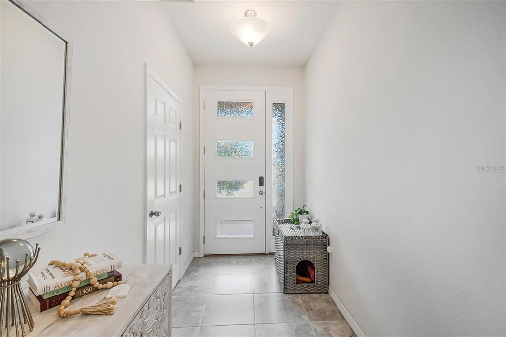 A bright entryway features a white front door with glass panels, tile flooring, and furniture — 2495 RAPOLLO DRIVE, KISSIMMEE, FL