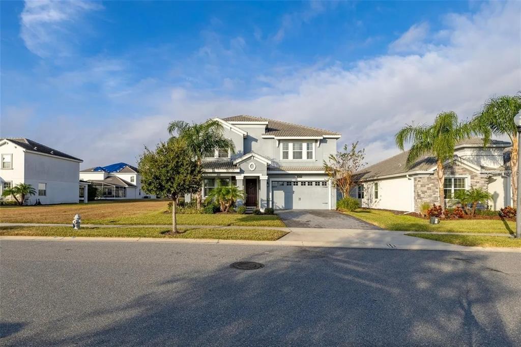 A two-story suburban house with a gray exterior, a two-car garage, and palm trees — 1474 OLYMPIC CLUB BOULEVARD, CHAMPIONS GATE, FL