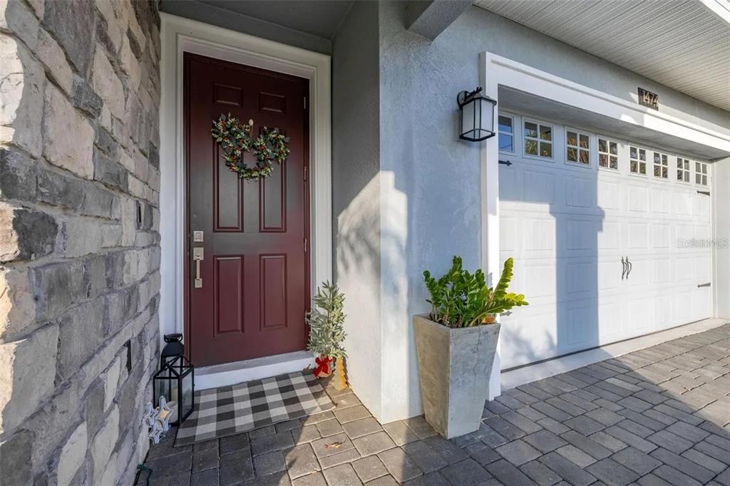 A front entryway features a dark red door, a stone wall, and a garage door — 1474 OLYMPIC CLUB BOULEVARD, CHAMPIONS GATE, FL