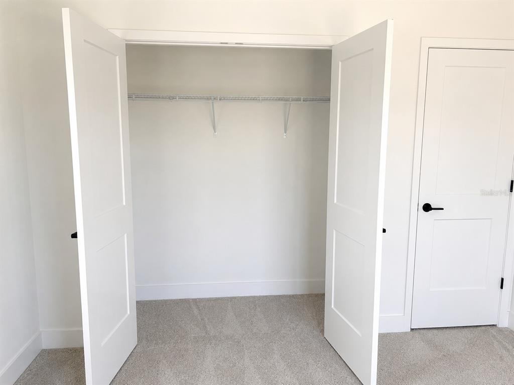 A closet with white double doors and a wire shelf stands next to a bedroom door — 1680 ANN ROSE WAY WAY, LEESBURG, FL