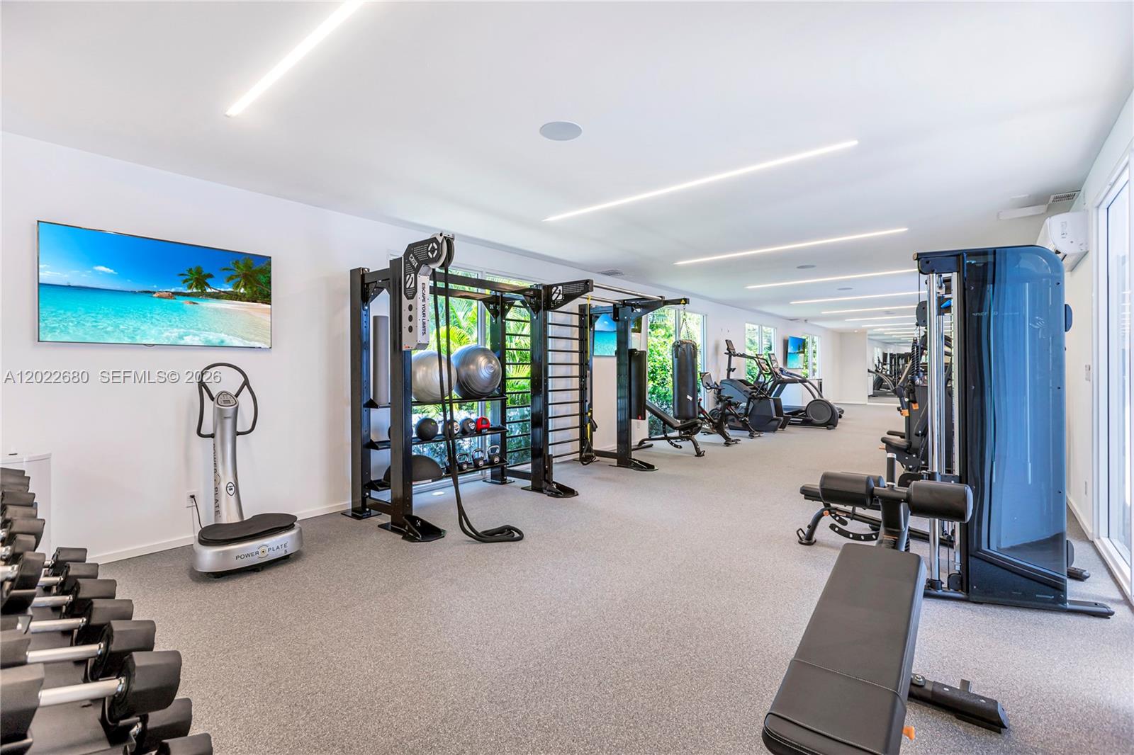 A modern gym features a variety of exercise equipment, weight racks, and a television screen — 10250 Collins Avenue # 307, Bal Harbour FL 33154, BAL HARBOUR, FL