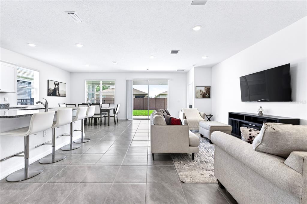 An open-concept living room and kitchen featuring tile flooring, a breakfast bar, and sliding doors — 4975 NW 39TH LOOP, OCALA, FL