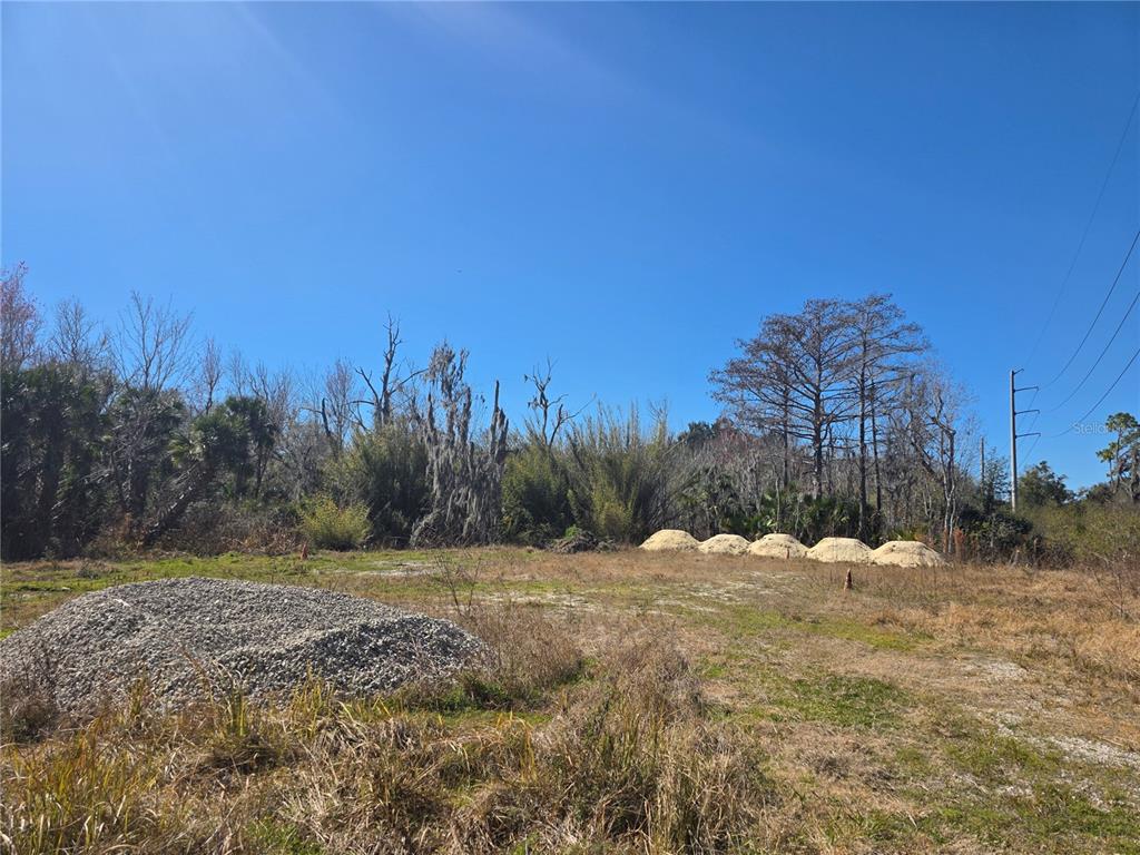 A vacant, grassy lot features a large pile of gravel and several mounds of sand — 470 N STATE ROAD 415, OSTEEN, FL