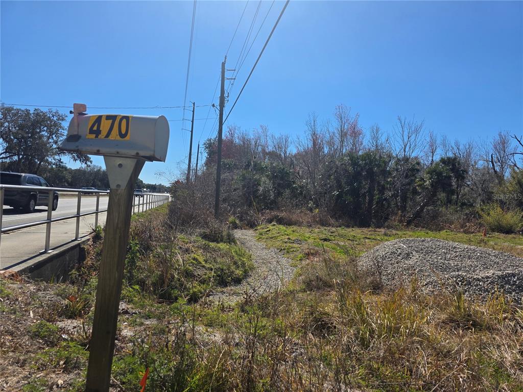 A mailbox labeled 470 stands beside a road next to a vacant, partially wooded lot — 470 N STATE ROAD 415, OSTEEN, FL