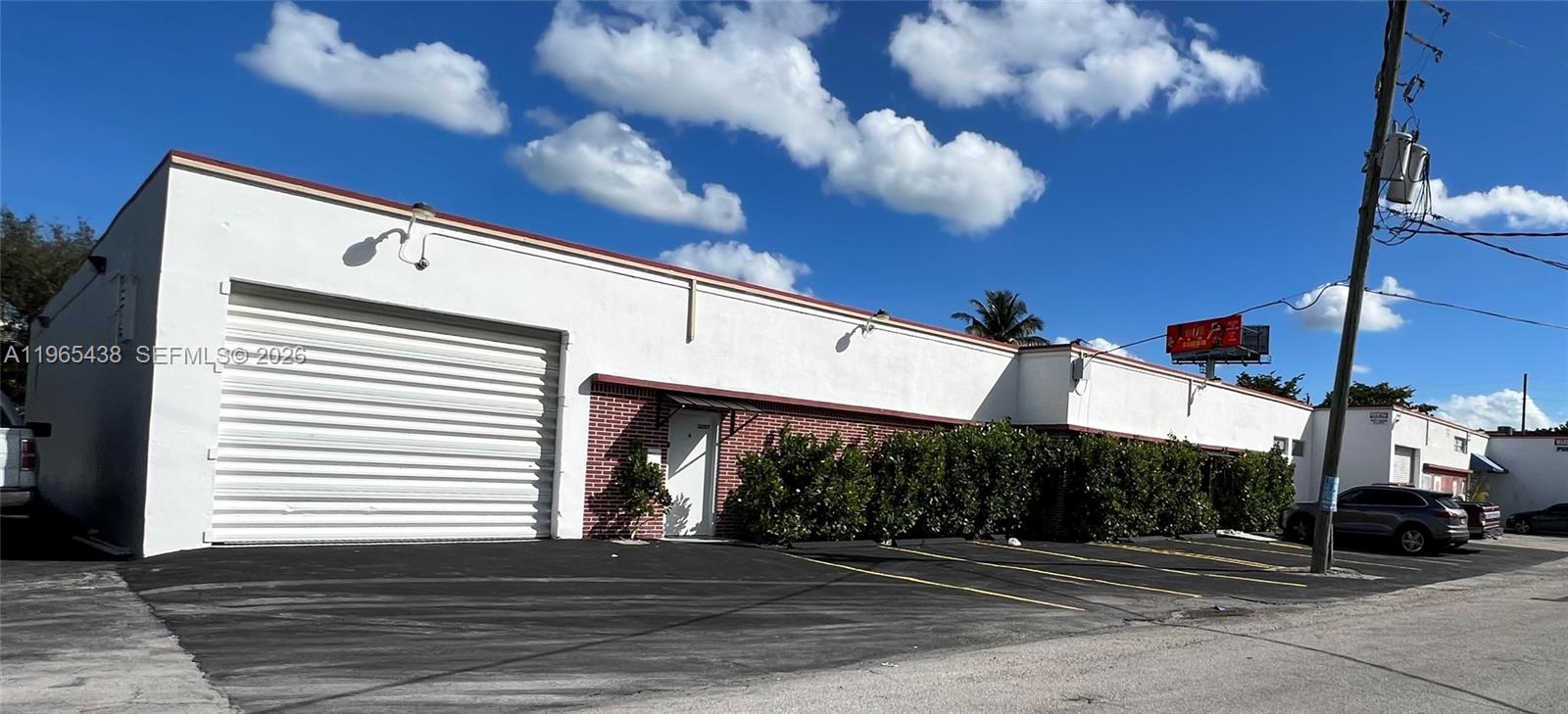 A white commercial building features a large roll-up garage door and a paved parking lot — 3257 NW 7 Ave Cir # A, Miami FL 33127, MIAMI, FL