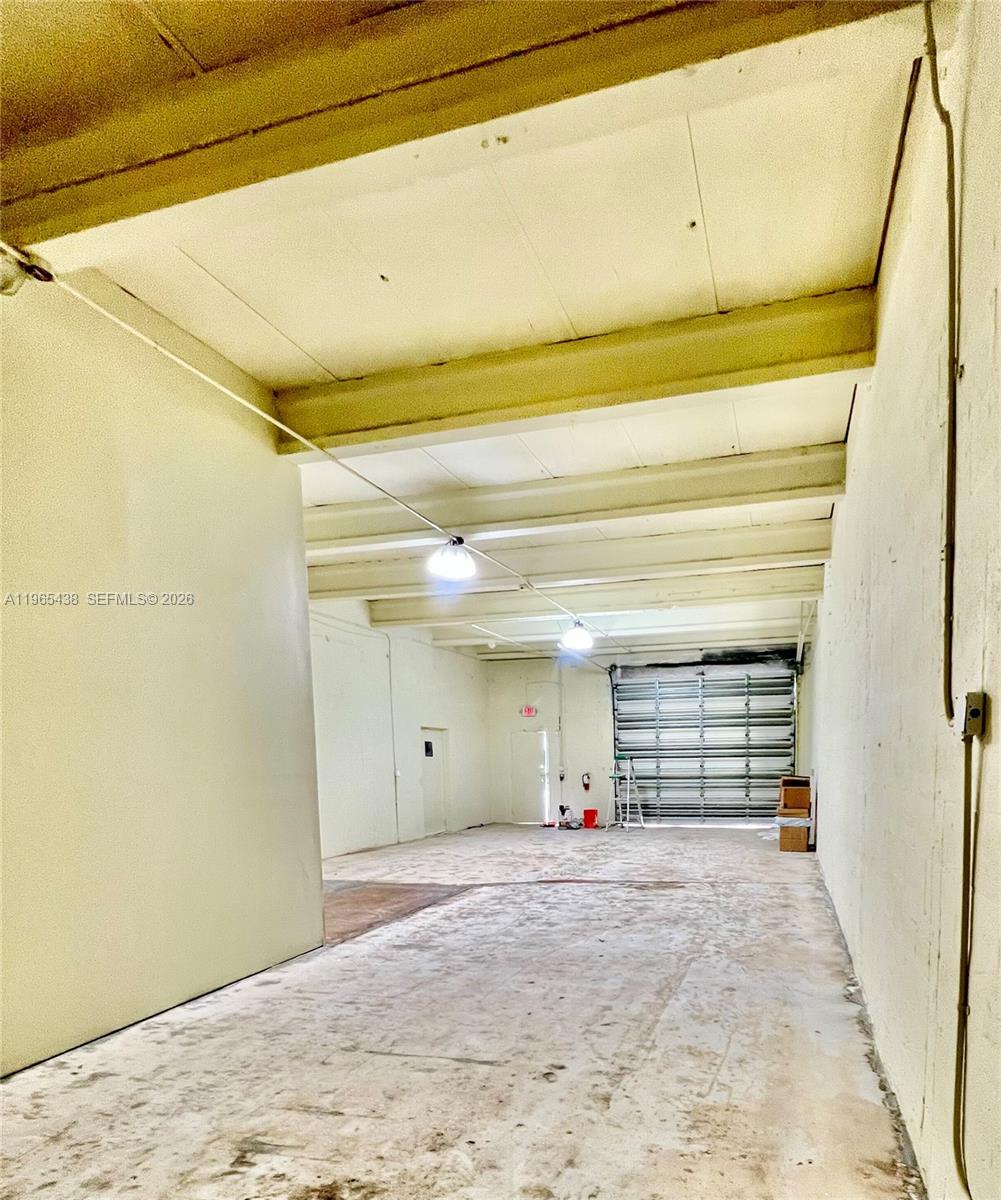 An empty industrial warehouse space features concrete floors, exposed ceiling beams, and a roll-up door — 3257 NW 7 Ave Cir # A, Miami FL 33127, MIAMI, FL